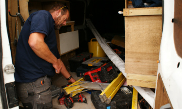 Picture of tradesman in back of the van with tools
